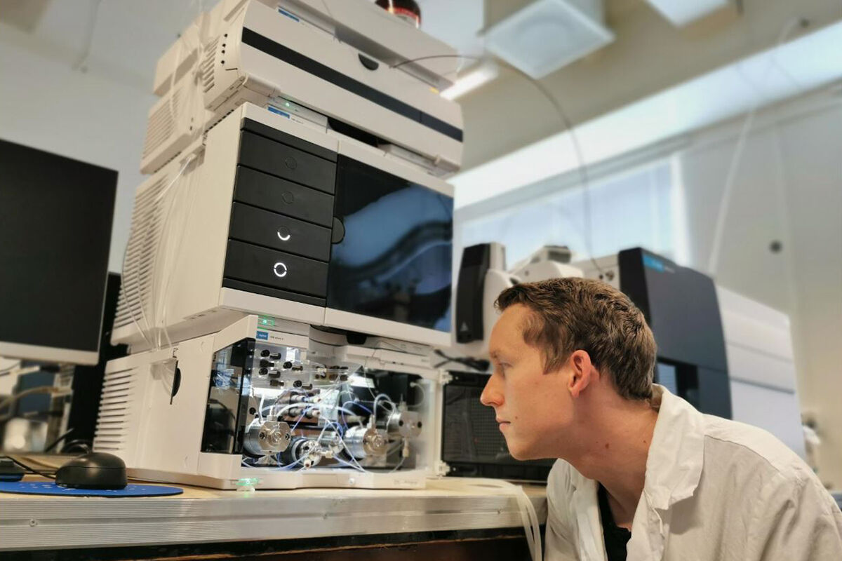 Frederik Hansen ved sida av analysemaskin i laboratoriet