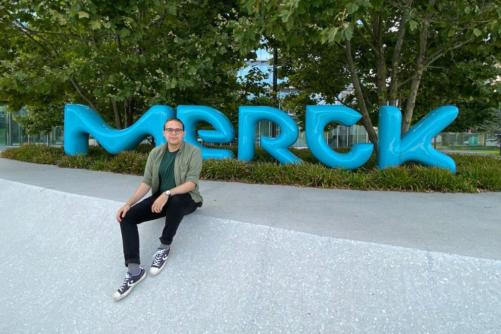 Denis Zosen framanfor logoen til selskapet Merck