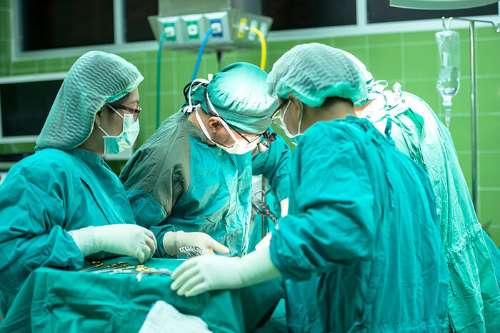 Legar og sjukepleiarar under operasjon i operasjonssal