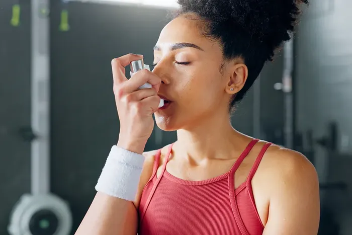 Kvinne i trenningssenter som briukar astmainhalator