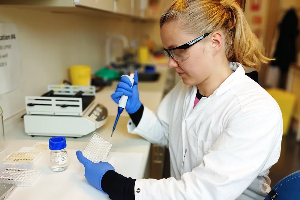 Maria Schüller i laboratoriet med vernebriller, dropeteljar og prøveutstyr