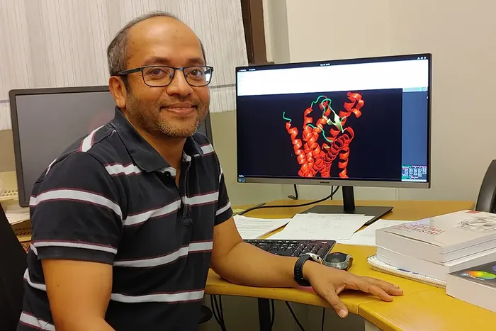 Osman Gani sit ved dataskjerm med modell av eit molekyl