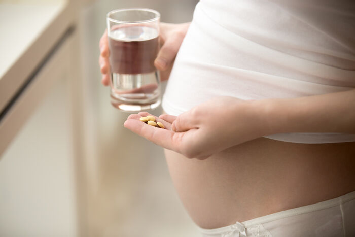 gravid kvinne med medisiner i hånden