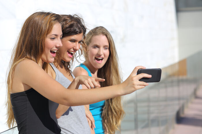 tre jenter som tar en selfie med en mobil
